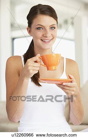 Stock Photograph - Young Woman Drinking Out Of An Orange Cup. Fotosearch