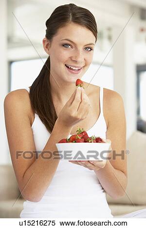 Stock Photography - Young Woman Eating A Bowl Of Fresh Strawberries. Fotosearch