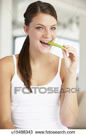 Stock Image - Young Woman Eating Celery Sticks. Fotosearch