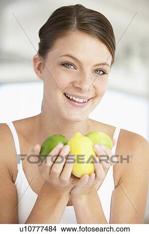 Young Woman Holding Fresh Fruit And Smiling At The Camera View Large Photo Image Picture - Young Woman Holding Fresh Fruit And Smiling At The Camera. Fotosearch
