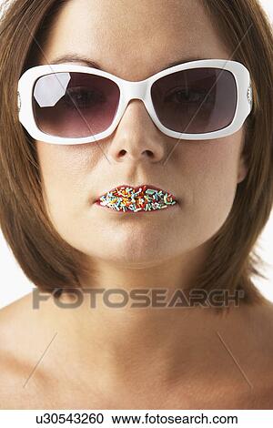 Stock Image - Young Woman Wearing Sunglasses With Sprinkles On Her Lips. Fotosearch
