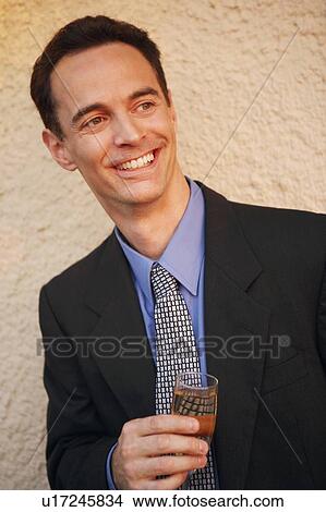 Picture - Close-up of a mature man holding a glass of champagne. Fotosearch