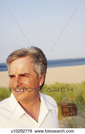 Stock Photo - Close-up of a mature man smiling on the beach. Fotosearch