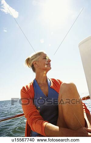 Stock Image - Close-up of a mature woman sitting in a boat and smirking. Fotosearch