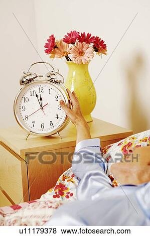 Close-up of a woman reaching for an alarm clock View Large Photo Image Stock Photo - Close-up of a woman reaching for an alarm clock. Fotosearch