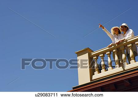 Low angle view of a mid adult couple standing on a terrace View Large Photo Image Stock Image - Low angle view of a mid adult couple standing on a terrace. Fotosearch