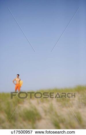 Mature man standing on the beach and holding a wooden surfboard View Large Photo Image Stock Photo - Mature man standing on the beach and holding a wooden surfboard. Fotosearch