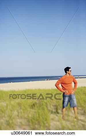 Mature man standing on the beach with his arms akimbo View Large Photo Image Stock Image - Mature man standing on the beach with his arms akimbo. Fotosearch