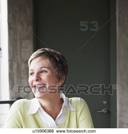 Stock Photo - Mature woman holding a champagne flute and smiling. Fotosearch