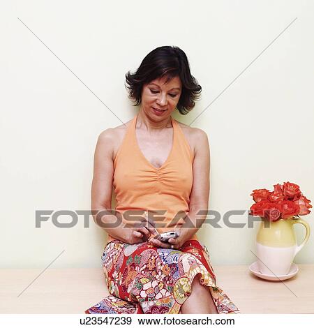 Stock Photo - Mature woman operating a personal data assistant. Fotosearch