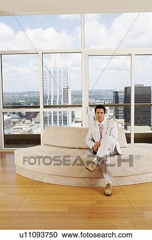 Portrait of a businessman sitting on a couch in an office View Large Photo Image Stock Image - Portrait of a businessman sitting on a couch in an office. Fotosearch