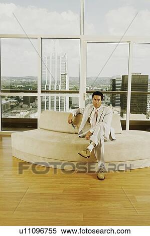 Stock Photography - Portrait of a businessman sitting on a couch in an office. Fotosearch