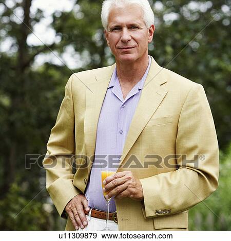 Portrait of a mature man holding a glass of juice View Large Photo Image Stock Photo - Portrait of a mature man holding a glass of juice. Fotosearch