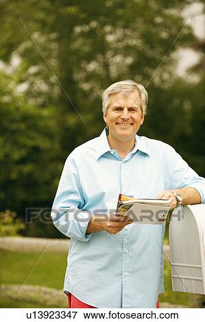 Portrait of a mature man standing beside a mailbox and holding mails View Large Photo Image Stock Photo - Portrait of a mature man standing beside a mailbox and holding mails. Fotosearch
