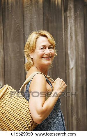 Portrait of a mature woman carrying a wicker basket and smiling View Large Photo Image Stock Image - Portrait of a mature woman carrying a wicker basket and smiling. Fotosearch