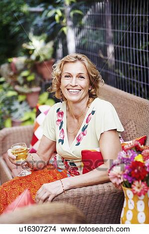 Portrait of a mature woman holding a glass of wine and smiling View Large Photo Image Picture - Portrait of a mature woman holding a glass of wine and smiling. Fotosearch