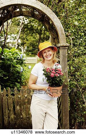 Portrait of a mature woman holding a potted plant and smiling View Large Photo Image Stock Photo - Portrait of a mature woman holding a potted plant and smiling. Fotosearch