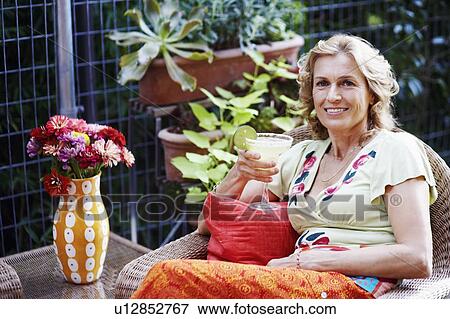 Portrait of a mature woman holding a glass of lemonade and smiling View Large Photo Image Stock Photo - Portrait of a mature woman holding a glass of lemonade and smiling. Fotosearch