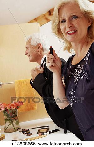 Portrait of a mature woman holding a lipstick with a mature man adjusting his bow tie View Large Photo Image Stock Photograph - Portrait of a mature woman holding a lipstick with a mature man adjusting his bow tie. Fotosearch