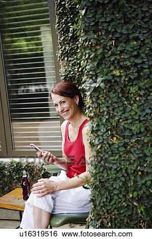 Stock Photograph - Portrait of a mature woman holding a mobile phone and smiling. Fotosearch