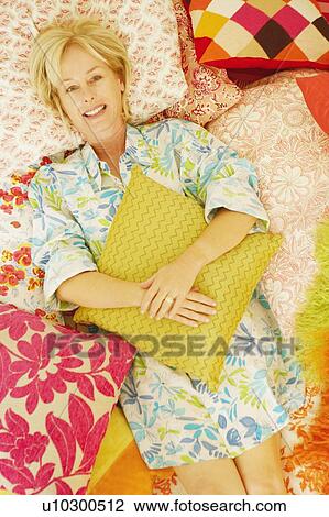 Stock Image - Portrait of a mature woman lying on the bed and smiling. Fotosearch
