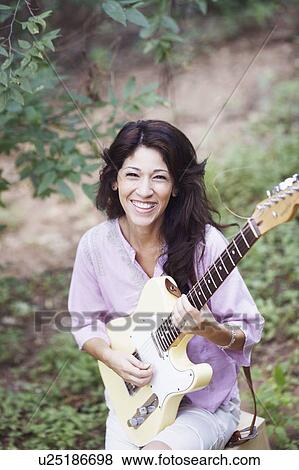 Stock Photo - Portrait of a mature woman playing the guitar. Fotosearch