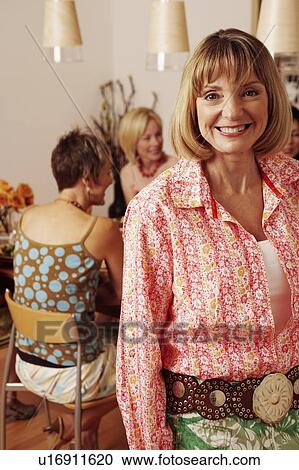 Portrait of a mature woman smiling and her friends sitting behind her View Large Photo Image Stock Image - Portrait of a mature woman smiling and her friends sitting behind her. Fotosearch