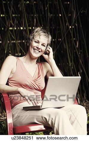 Portrait of a mature woman using a laptop and smiling View Large Photo Image Stock Image - Portrait of a mature woman using a laptop and smiling. Fotosearch