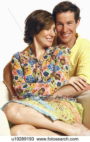 Stock Image - Portrait of a mid adult man embracing a mid adult woman and smiling. Fotosearch
