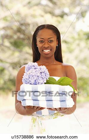 Portrait of a mid adult woman holding folded towels and a flower View Large Photo Image Stock Photograph - Portrait of a mid adult woman holding folded towels and a flower. Fotosearch
