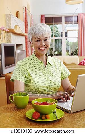 Portrait of a senior woman using a laptop and smiling View Large Photo Image Stock Photo - Portrait of a senior woman using a laptop and smiling. Fotosearch