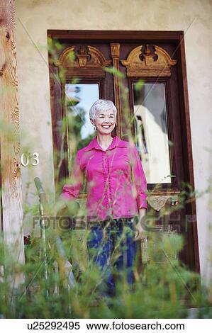 Senior woman standing in front of a closed door and smiling View Large Photo Image Stock Photography - Senior woman standing in front of a closed door and smiling. Fotosearch