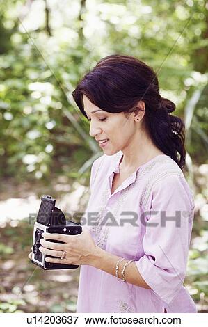 Stock Photo - Side profile of a mature woman holding a camera. Fotosearch