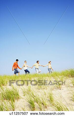 Two mature couples holding hands and walking on the beach View Large Photo Image Stock Photo - Two mature couples holding hands and walking on the beach. Fotosearch