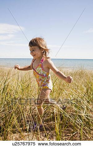 Stock Photography - "Beaver Island, Girl running in grass on beach, Beaver Island, Michigan, USA". Fotosearch