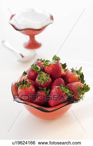 Stock Photograph - Bowl of strawberries with whipped cream in background. Fotosearch
