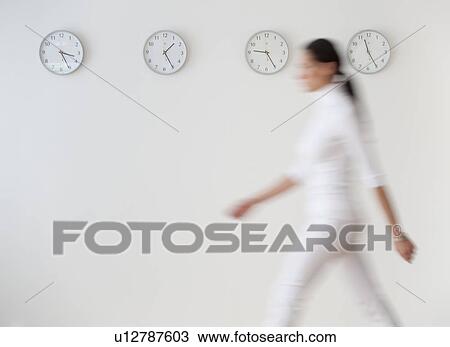 "Business woman walking along wall with clocks, blurred motion" View Large Photo Image Stock Image - "Business woman walking along wall with clocks, blurred motion". Fotosearch
