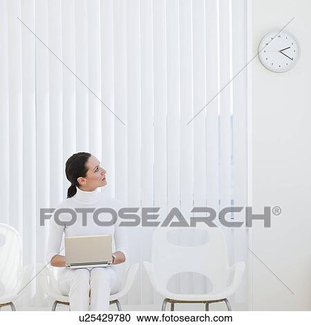 Businesswoman looking at clock in waiting room View Large Photo Image Stock Image - Businesswoman looking at clock in waiting room. Fotosearch