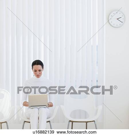Stock Photo - Businesswoman using laptop in waiting room. Fotosearch