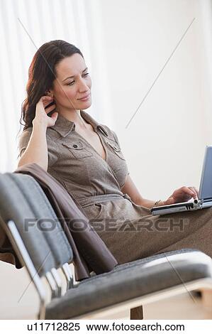 Stock Photography - Businesswoman using laptop in waiting room. Fotosearch