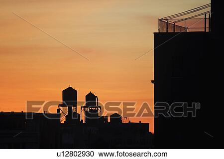 Stock Image - "Cityscape with silhouettes of water towers at sunset, New York City, New York, USA". Fotosearch