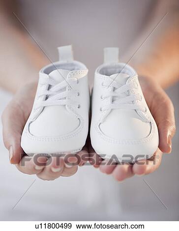 Stock Photo - Close-up of woman holding baby shoes. Fotosearch
