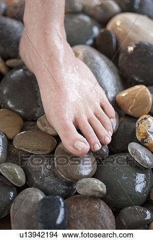 Picture - Close-up of woman's foot on pebbles. Fotosearch