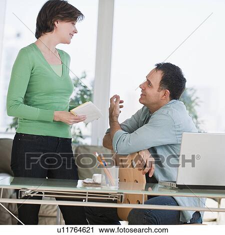 Stock Image - Colleagues talking in office. Fotosearch