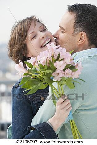 "Couple embracing, woman holding flowers" View Large Photo Image Stock Photo - "Couple embracing, woman holding flowers". Fotosearch