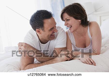 Picture - Couple lying side by side on bed. Fotosearch