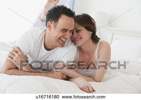 Stock Image - Couple lying side by side on bed. Fotosearch