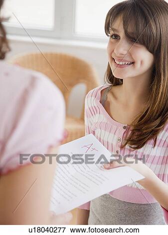 Stock Photo - Daughter (10-12 years) showing mother essay result. Fotosearch