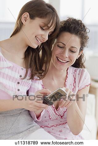 Stock Photo - Daughter (10-12 years) teaching mother how to send text messages. Fotosearch