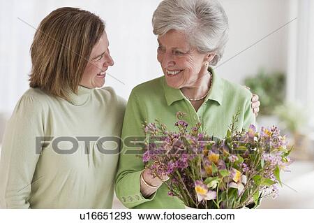 Daughter hugging mother holding flowers View Large Photo Image Stock Image - Daughter hugging mother holding flowers. Fotosearch